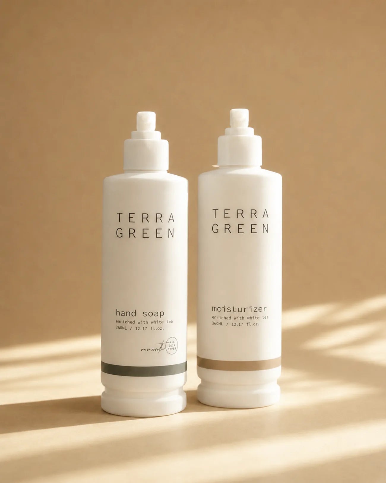Terra Green hand soap and moisturiser bottles side by side on a warm neutral background