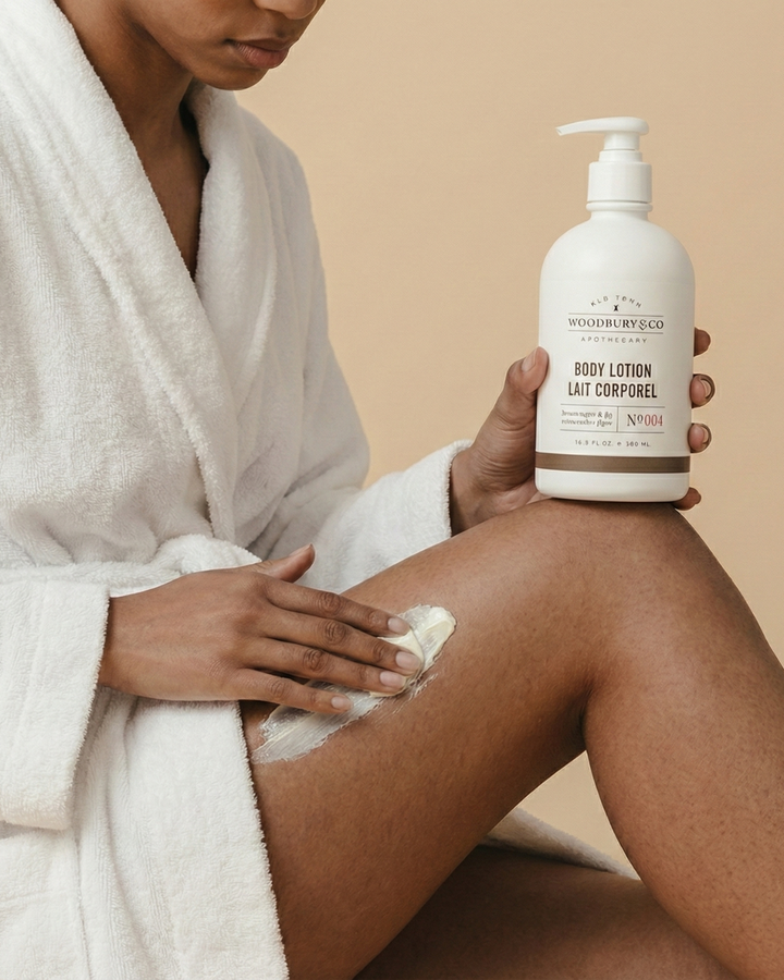 Person applying lotion to their leg with a bottle of Woodbury & Co. lotion.