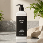 Kenneth Cole Shampoo bottle on a marble surface with plants in the background