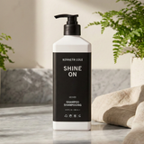 Kenneth Cole Shampoo bottle on a marble surface with plants in the background