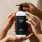 Kenneth Cole Shine On shampoo bottle held by hands against a neutral background