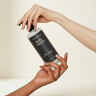 Hand holding a bottle labeled 'Nice Touch' against a neutral background