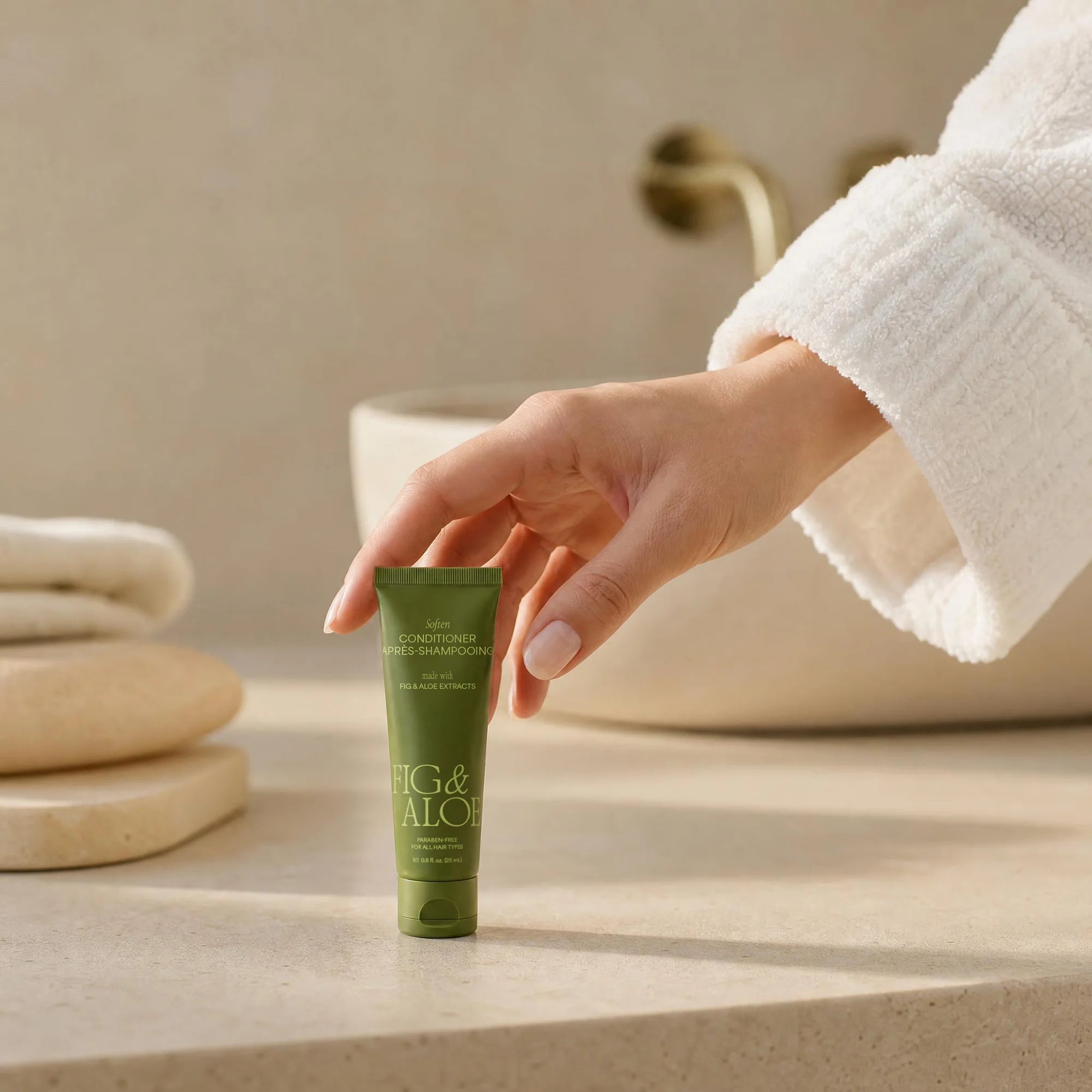 Guest reaching for a Fig and Aloe travel-size amenity