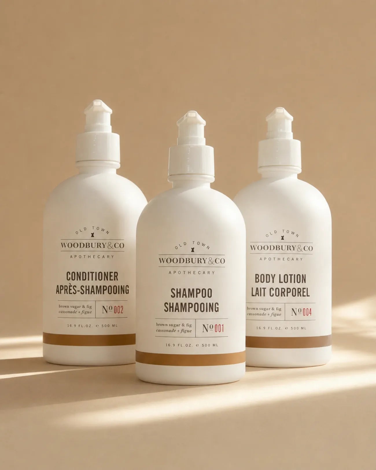 Woodbury & Co conditioner, shampoo and body lotion bottles grouped on a warm neutral background